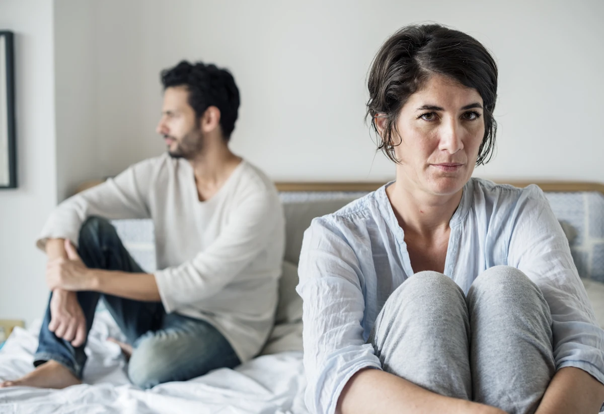 Un homme et une femme assis dans le lit qui s'ignorent